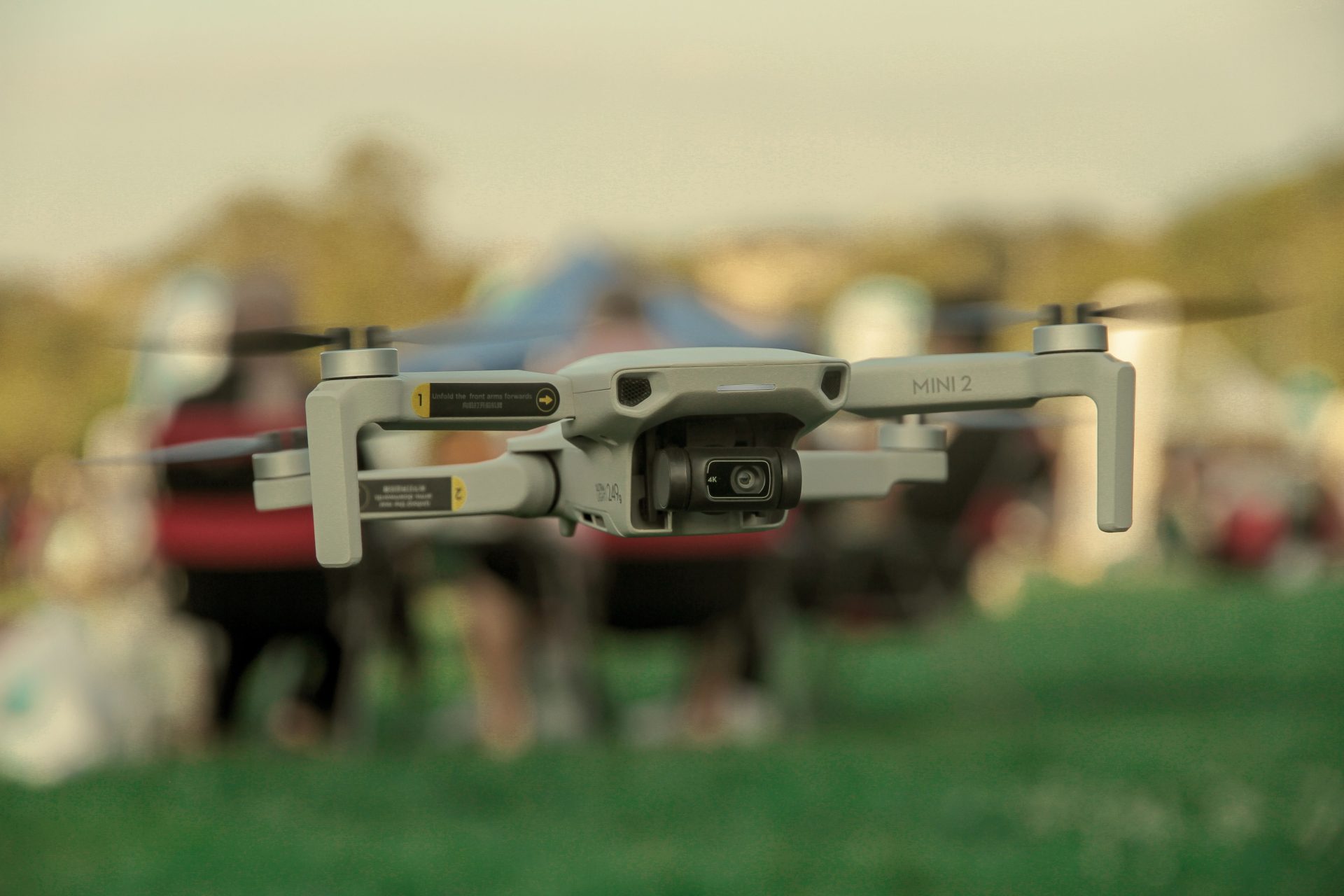 Eine DJI Mini 2-Drohne im Flug im Freien vor unscharfem Hintergrund.