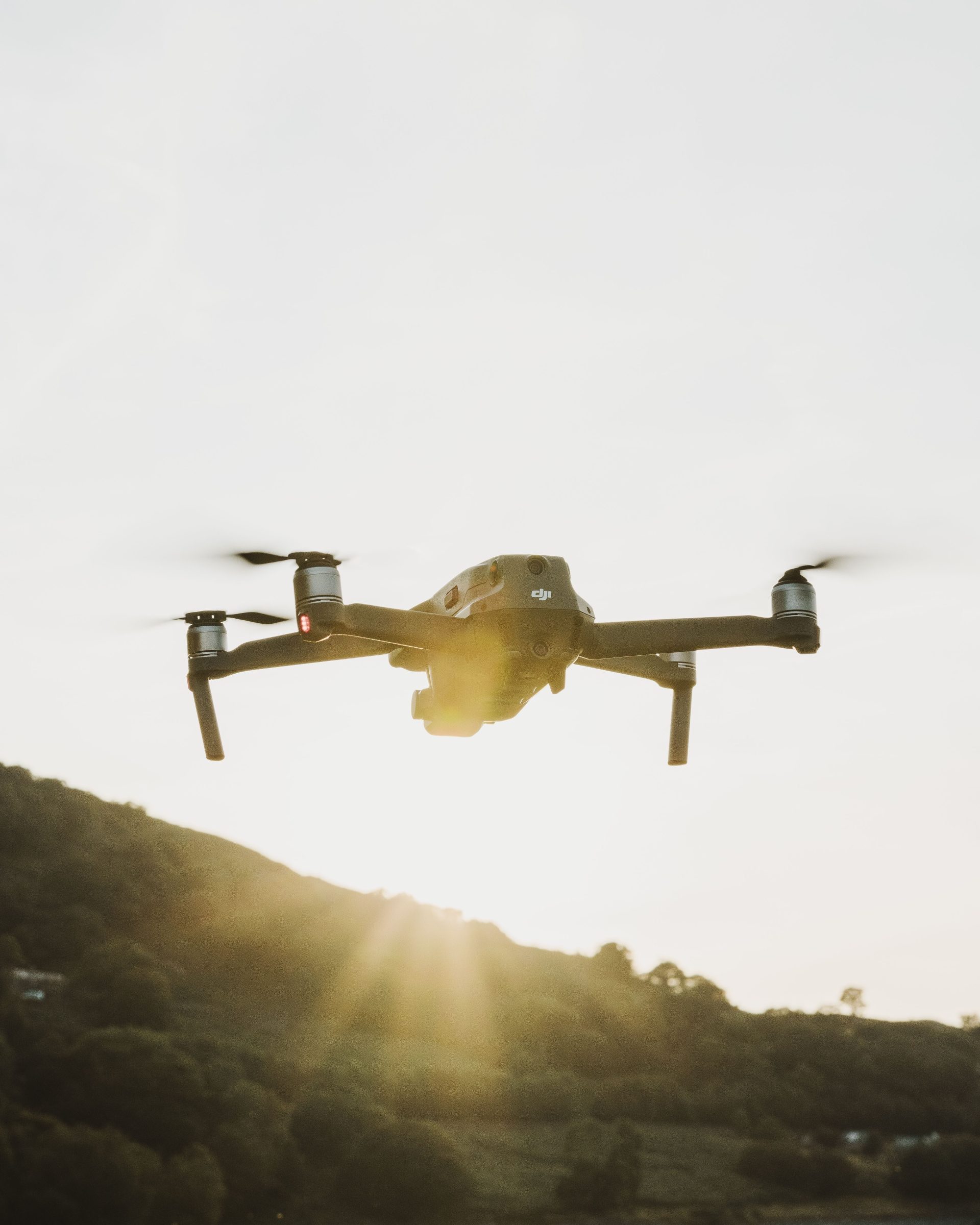 Eine Drohne fliegt bei Sonnenaufgang über hügeliges Gelände und demonstriert dabei Technologie sowie Flugfähigkeiten.