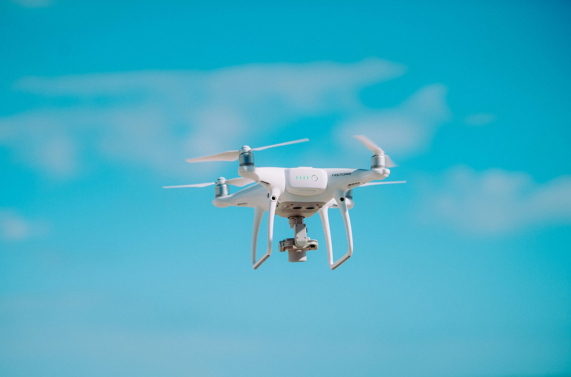 Weißer Quadrocopter im Flug bei Tageslicht